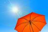 photo of orange umbrella under full sun with blue sky